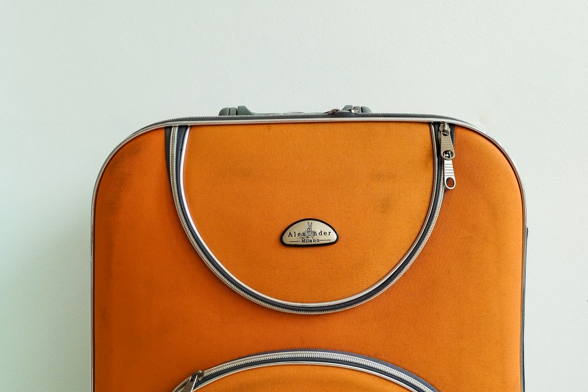 An orange hard-shell suitcase with handle and wheels