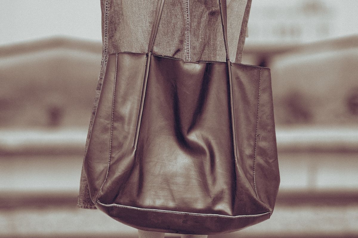 A leather tote bag carried with a denim outfit