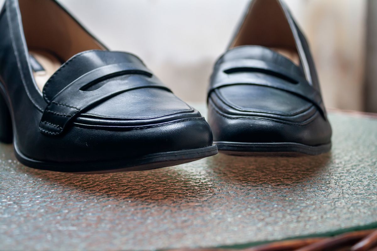 Black leather shoes resting on a glass table