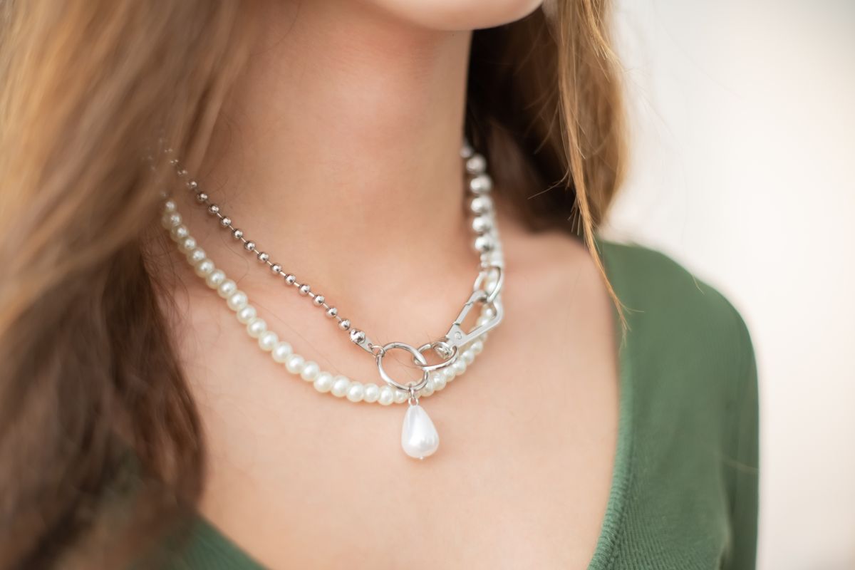 Close-up of a pearl strand clasped with a silver chain, worn on a neck