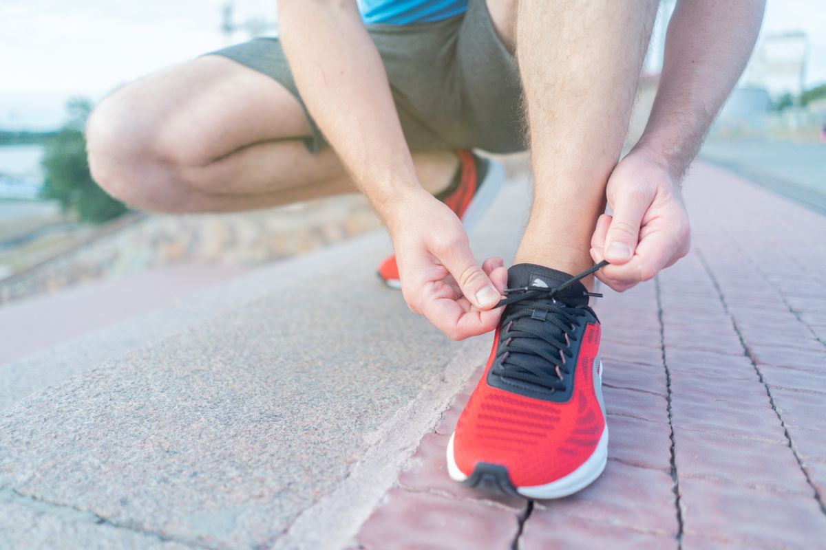 Close-up of a person tying the laces of a red sneaker