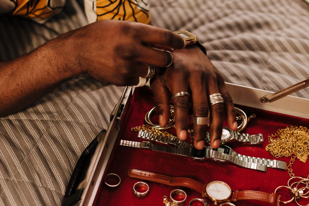 A man sorting gold chains, rings and watches inside a red-lined jewellery case
