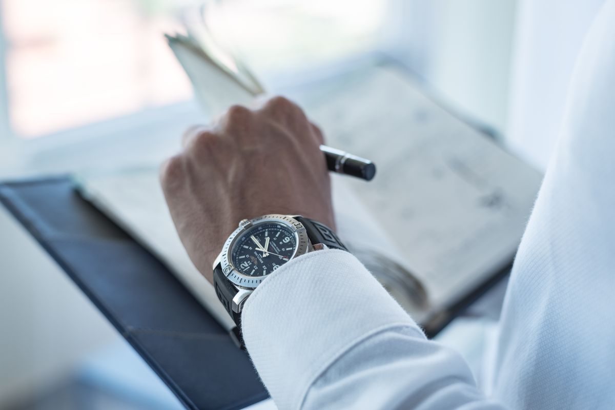 A person wearing a silver and black watch on the wrist