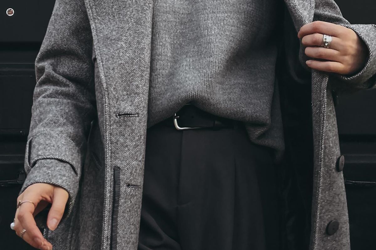 A grey herringbone wool coat worn open over a grey turtleneck